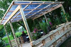 a wooden structure with potted plants on it in the middle of a garden area