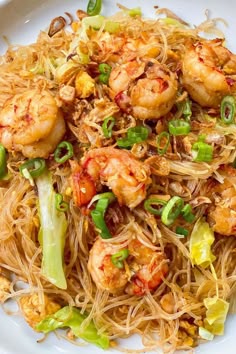 a white plate topped with noodles and shrimp