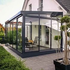 a house with glass walls and doors on the outside, in front of it is a patio