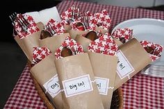 some brown paper bags with forks and spoons in them on a red checkered table cloth