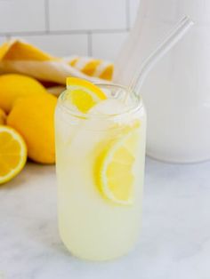 a glass filled with lemonade next to sliced lemons