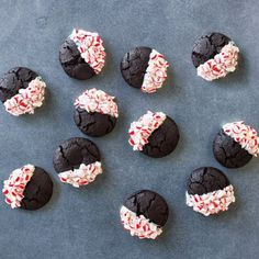 chocolate cookies with white and red sprinkles are arranged on a gray surface