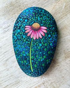 a painted rock with a pink flower on it