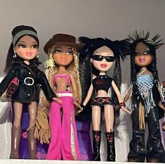 five dolls are lined up on the shelf together, all wearing clothes and hats with fringes