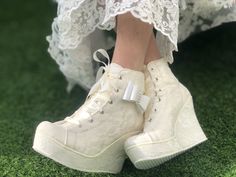 a close up of a person's foot wearing white shoes and lace on grass