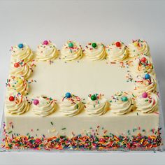 a cake with white frosting and colorful sprinkles on the top layer