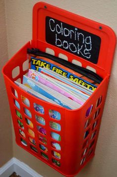 a red plastic basket holding books and folders with writing on the side that says coloring book