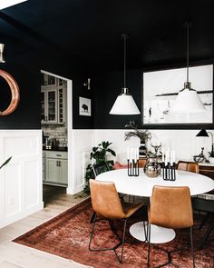 a black and white dining room with wooden chairs, rugs and hanging pendant lights