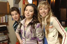 three young people standing next to each other in front of a television set and bookshelf