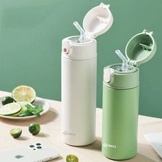 thermos and limes are sitting next to each other on a table with a cell phone