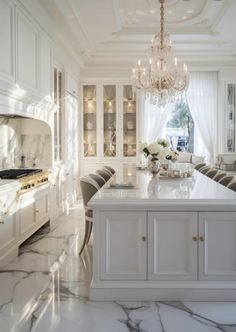 a large kitchen with marble counter tops and white cabinets, chandelier hanging from the ceiling