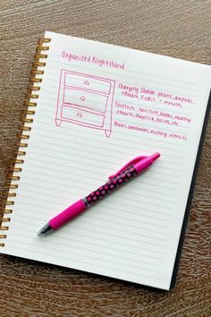 a pink pen sitting on top of a notebook