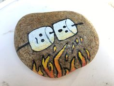 two marshmallows sitting on top of a rock with flames painted on it