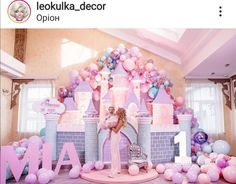 a woman standing in front of a castle with balloons on the walls and decorations around it