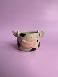 a ceramic cow cup on a purple background