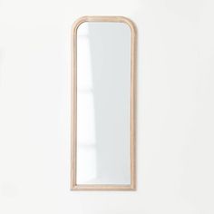 a white wall with a wooden mirror on it