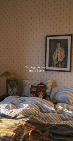 a bed with a book on top of it next to a lamp and framed photograph