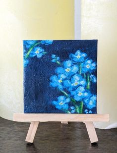 a painting on a wooden easel with blue flowers