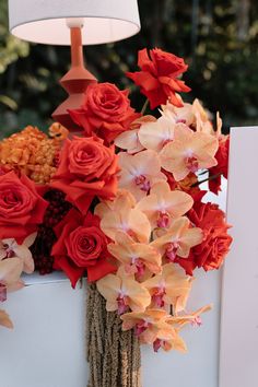 an arrangement of flowers is displayed on a table next to a lamp and greeting card