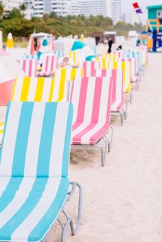 beach chairs and umbrellas lined up on the sand