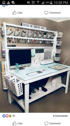 a white desk with a computer on it and lots of cups hanging from the wall