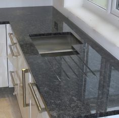 a kitchen counter with black granite top and stainless steel sink