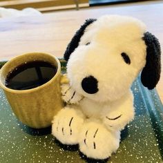 a stuffed dog sitting next to a cup of coffee