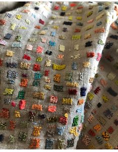 a close up of a piece of cloth covered in small colorful squares and crosses on it