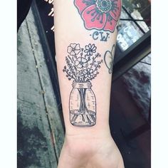 a woman's arm with a flower vase tattoo on it