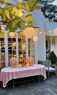 a table that has some lights hanging from it's branches on the outside of a building