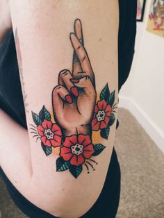 a woman's arm with a flower and peace sign tattoo on it, while holding her hand up in the air