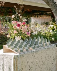 a table topped with a vase filled with pink flowers next to a white table cloth