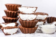 chocolate cups filled with marshmallows and topped with whipped cream, on a white surface