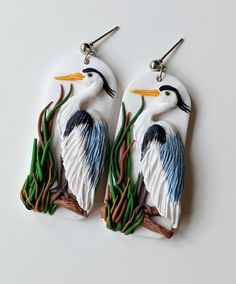 two white and blue bird shaped earrings on top of each other