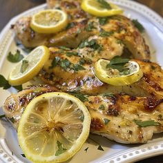 grilled chicken with lemons and herbs on a white plate