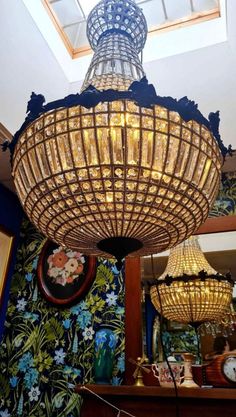 a chandelier hanging from the ceiling in a room with floral wallpaper and blue walls