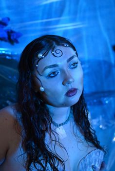 a woman with dark hair and blue eyes is posing for a photo in the water