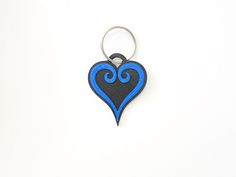 a blue and black heart shaped keychain on a white surface with a silver ring