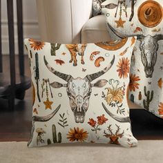 two decorative pillows with longhorns and flowers on them are sitting next to each other