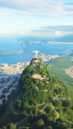 an aerial view of a city on top of a hill with water and mountains in the background