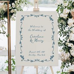 an easel with a wedding sign on it and flowers in front of the frame