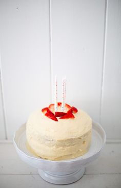 a white cake with strawberries on it and two candles sticking out of the top