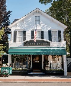 a store front with an american flag on the awning and horse statues in front