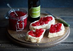 two pieces of bread with jam on them next to a bottle of wine and knife