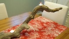 a candle is lit in the middle of a tree branch on a dining room table