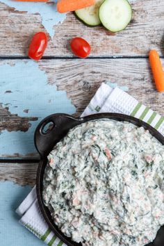 a bowl of dip surrounded by vegetables and cucumbers