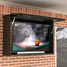 a basketball game is on the tv screen in front of a brick wall and window