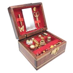 an open wooden box with jewelry inside on a white surface, including scissors and other items