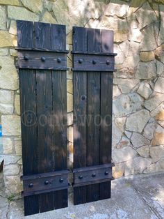 two wooden doors sitting next to a stone wall