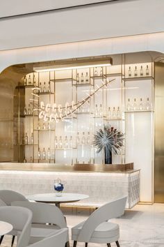 the interior of a modern restaurant with white chairs and marble counter tops, along with an elegant chandelier